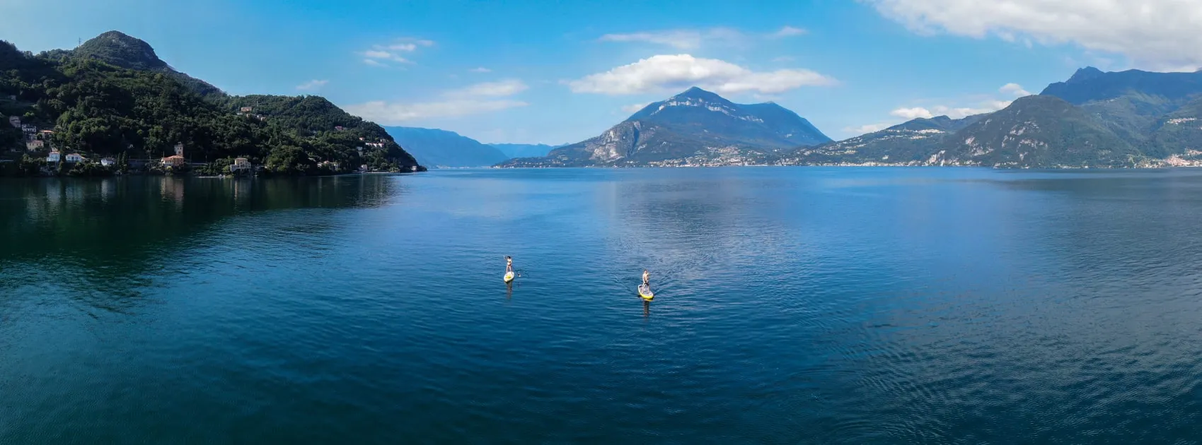 People paddleboarding on Lake Como with mountain views